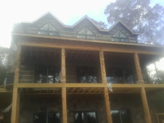 Dormers and porch framing on a large log home under construction — Roof Coating work by our crew in Oakdale